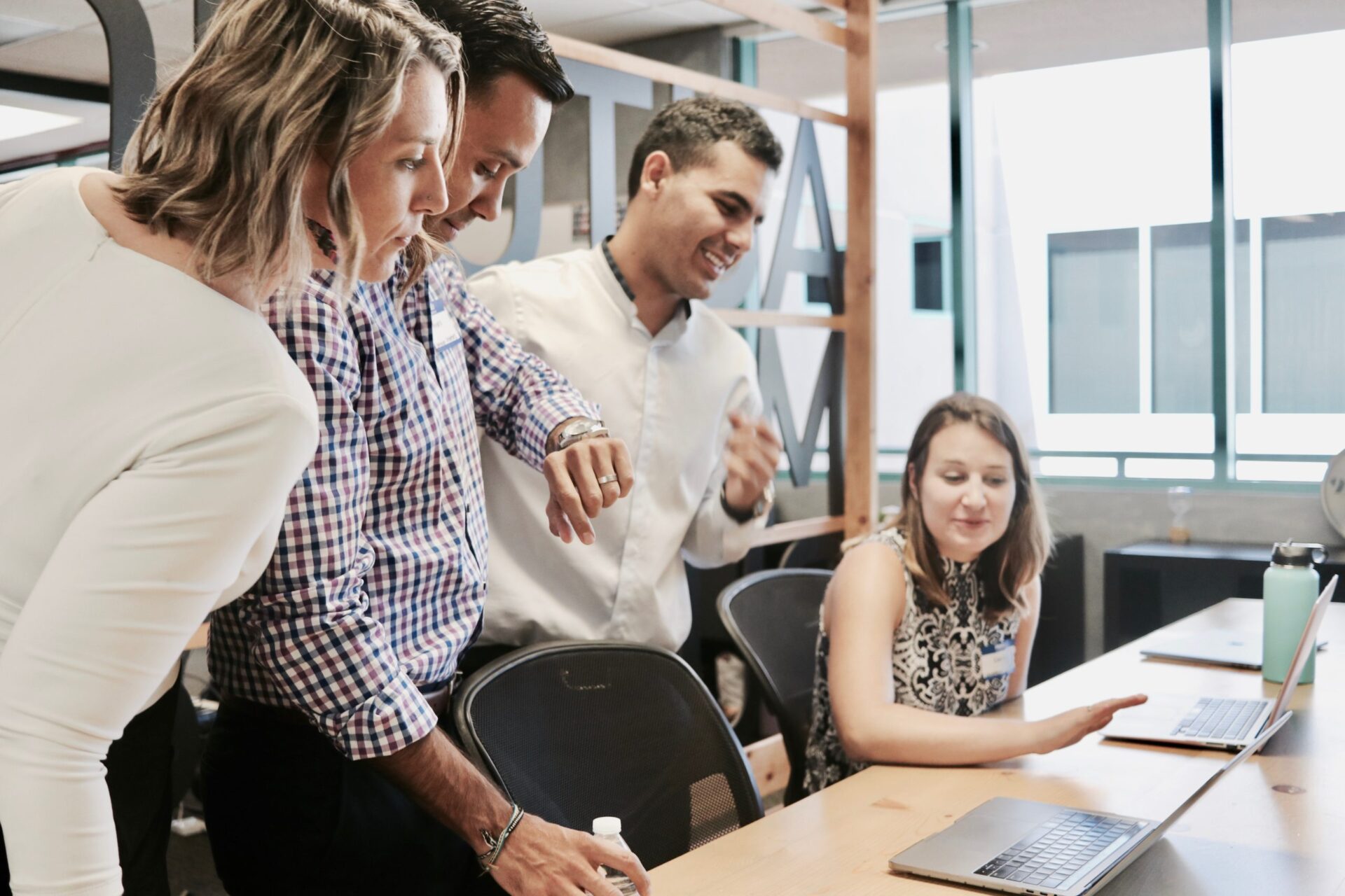 A group of people in an office looking at two laptops