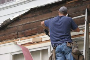 man repairing siding on rental home