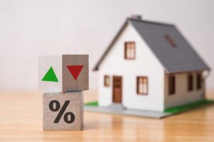 Wooden blocks percentage sign, arrow up and down with house model background. Central bank FED control interest rate increase or decrease effect to house price, monthly payment, buying home concept.