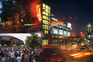 Arena District in Columbus, Ohio at night, featuring neon-lit restaurants, a crowd gathered outside Nationwide Arena for a concert, and the illuminated Arena District sign with downtown traffic in the foreground.